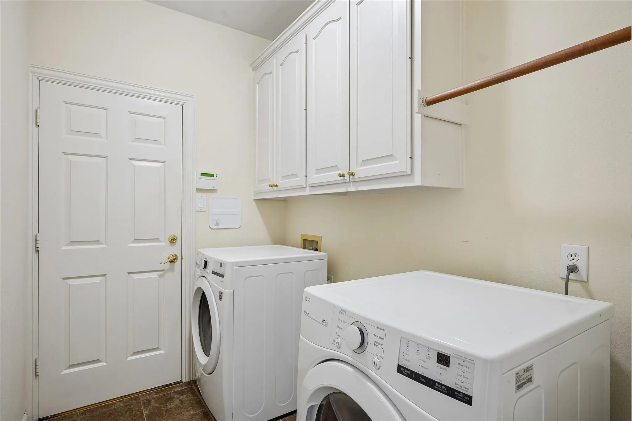 Laundry area featuring white cabinetry, a built-in hanging rod, and durable tile flooring