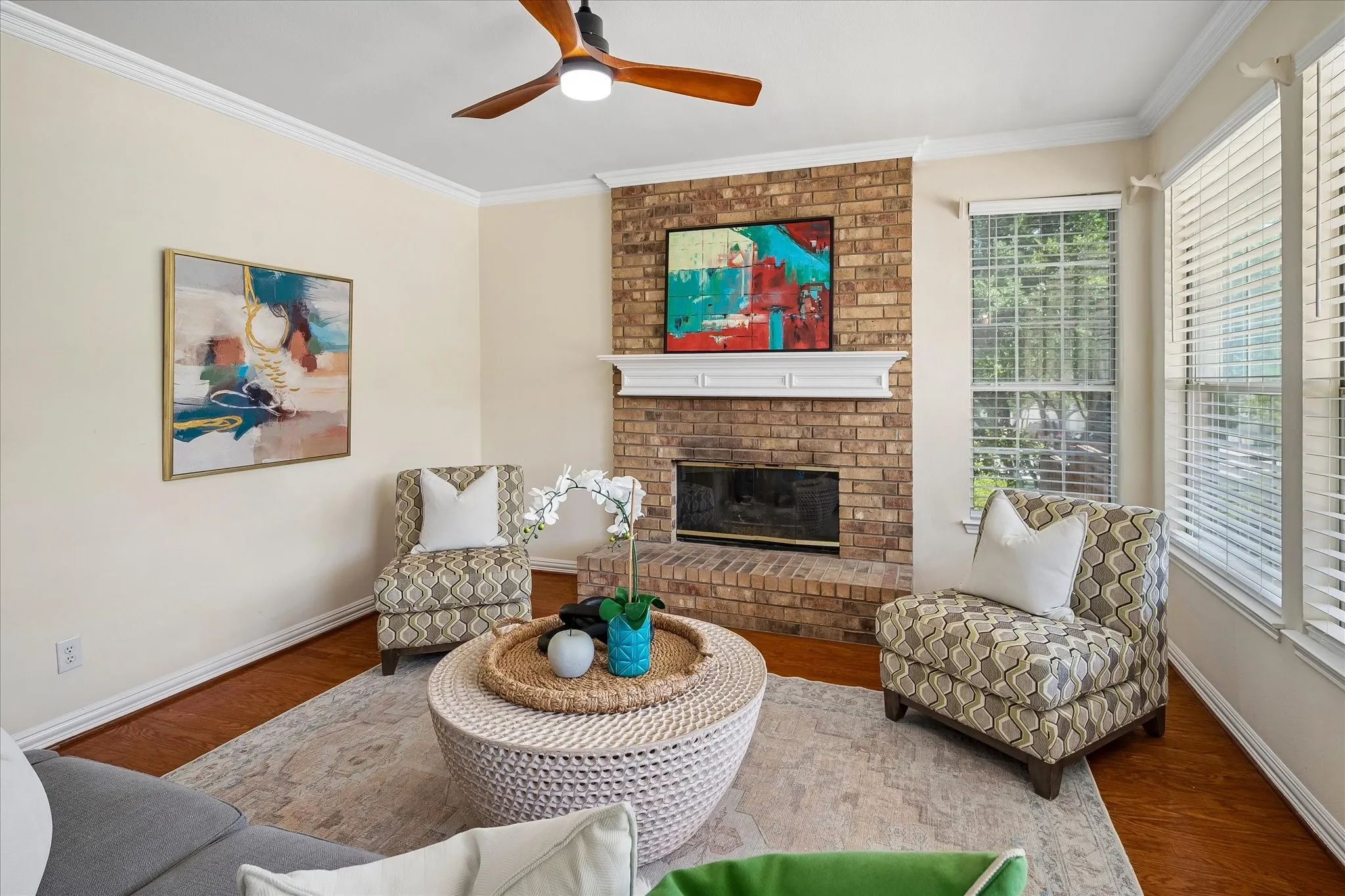 Brick fireplace with a white mantel, wood-finish flooring, and crown molding