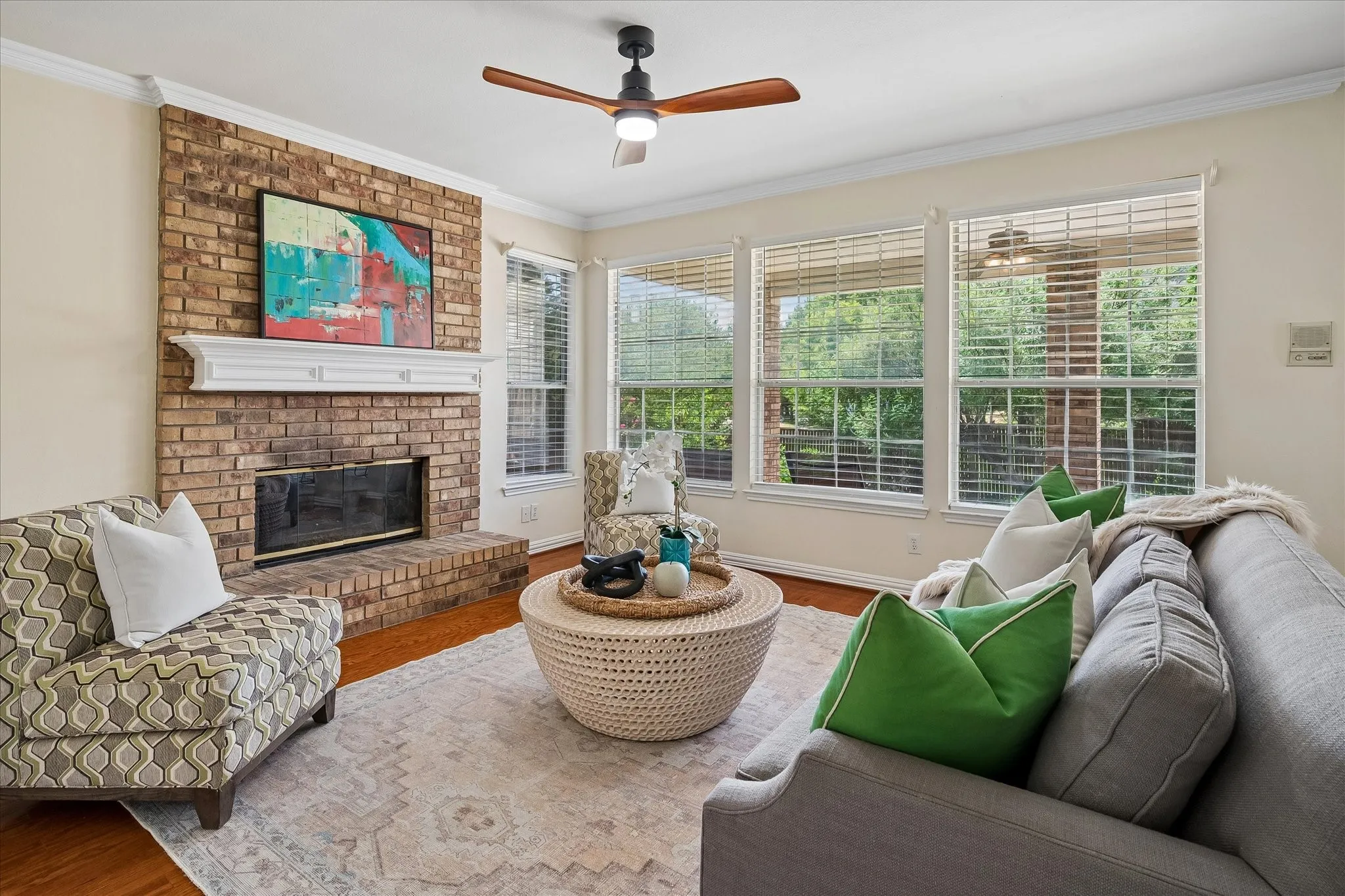Brick fireplace with a white mantel, wood-finish flooring, and crown molding