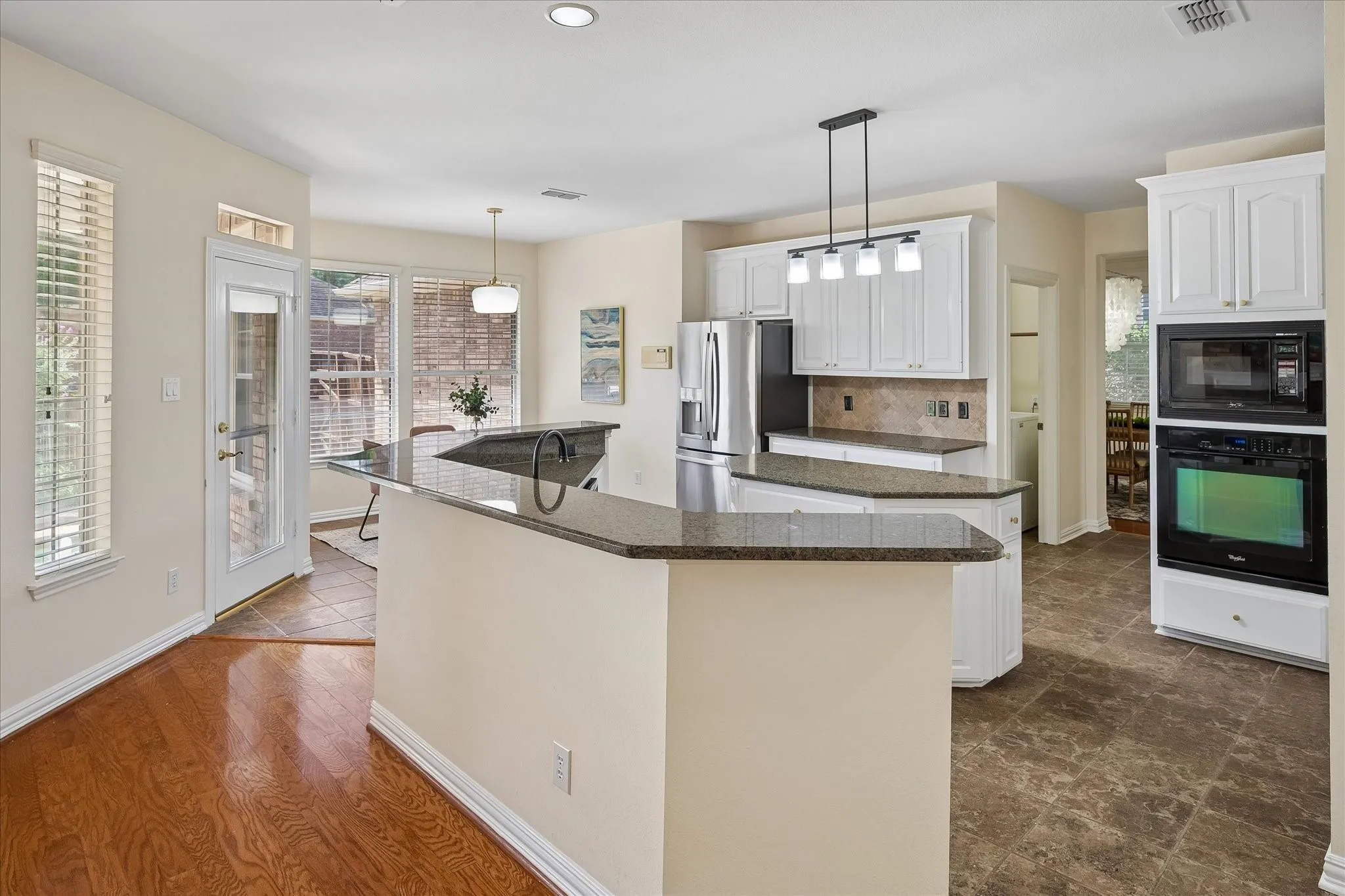Kitchen featuring white cabinetry, granite countertops, stainless steel appliances, a built-in oven and microwave, and wood-finish flooring