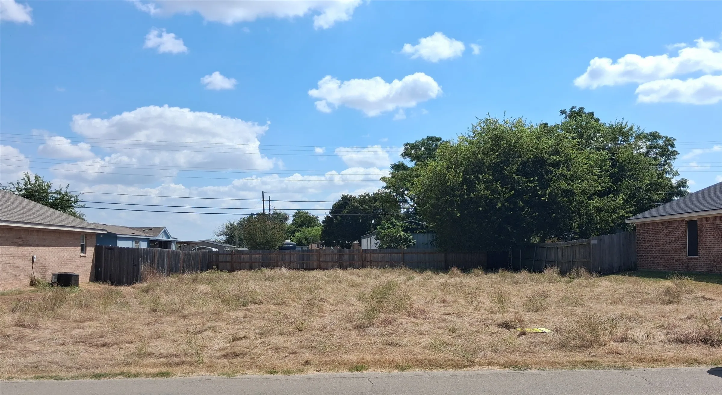 Expansive lot with partial wood fencing and mature trees