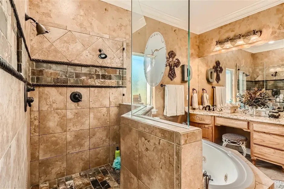 Walk-in shower with tile surround and stone accent band, frameless glass enclosure, jetted soaking tub, dual vanity with wood cabinetry, and extensive counter space
