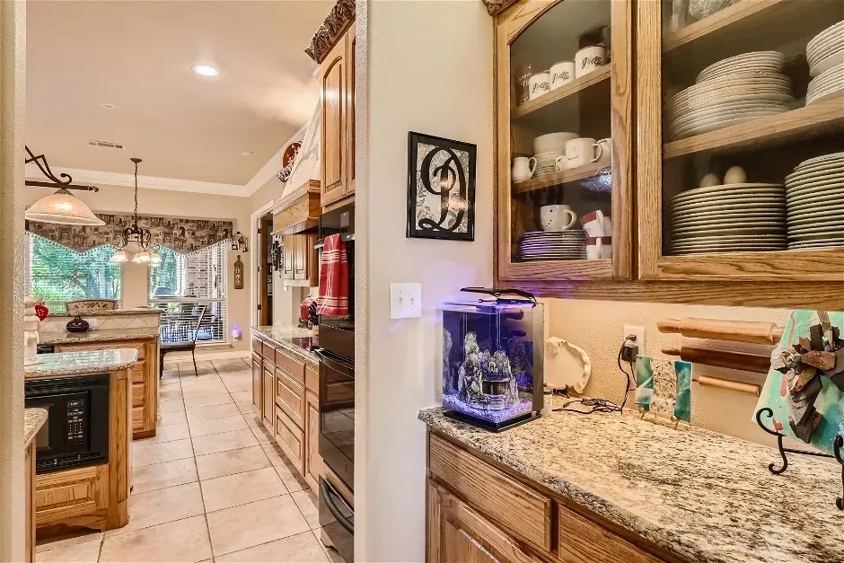 Kitchen featuring warm wood cabinetry, granite countertops, built-in microwave, and tile flooring