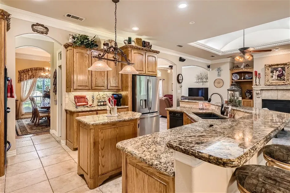 Kitchen featuring an island, light wood cabinetry, granite countertops, and tile flooring