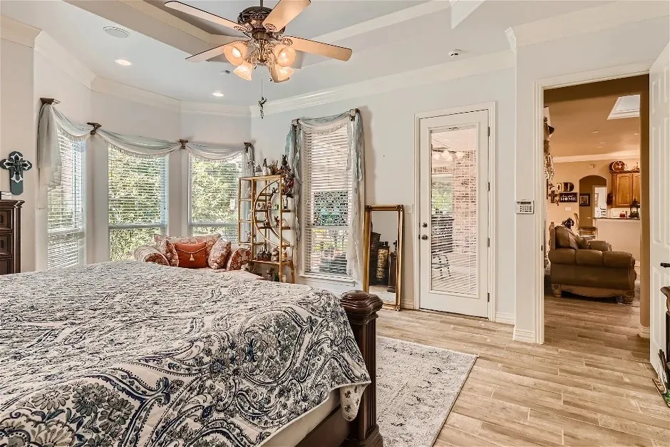Tray ceiling with a ceiling fan, bay window with multiple windows, wood-finish flooring, and a glass-paneled door
