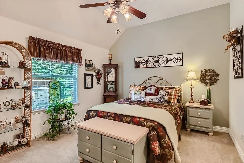 Vaulted ceiling with a ceiling fan, window with blinds, carpeted flooring, and light-toned wall paint