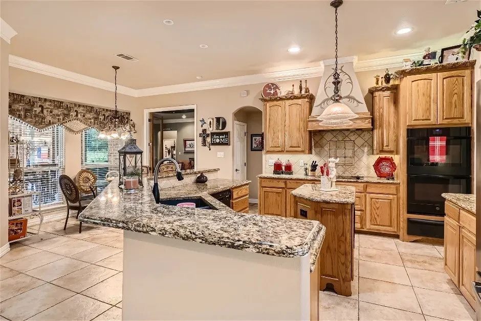 Kitchen featuring light wood cabinetry, granite countertops, and built-in double ovens