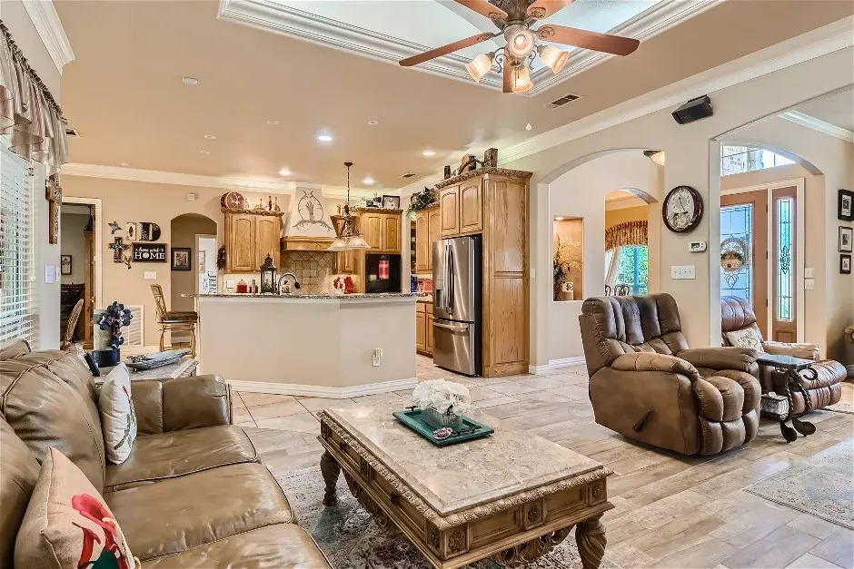 Tray ceiling with an overhead fan, recessed lighting, and crown molding