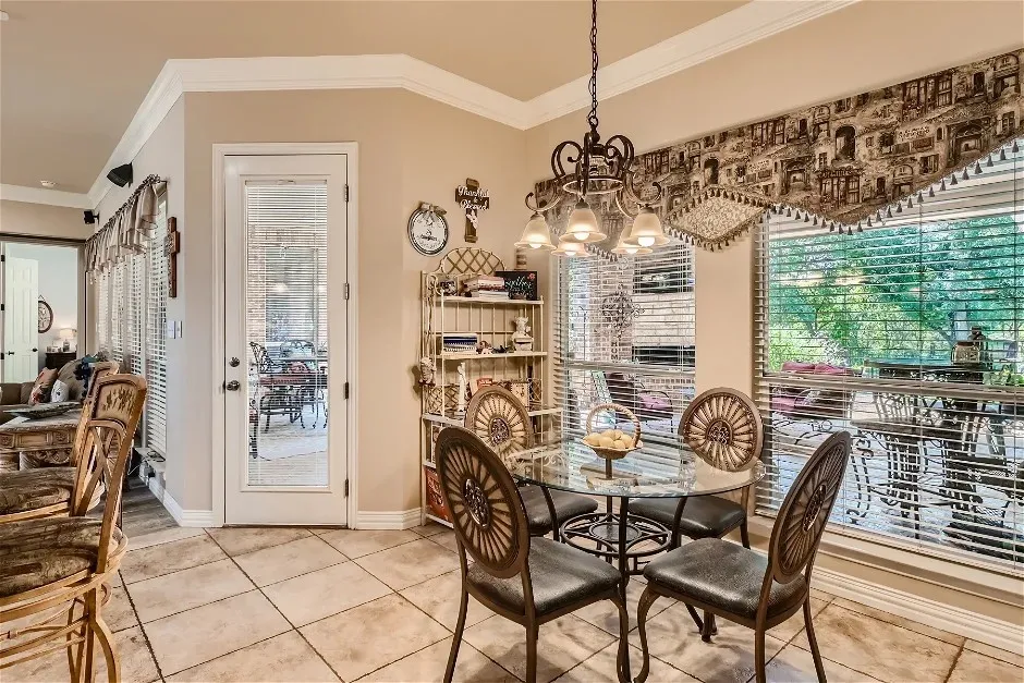 Tiled flooring extends throughout this space, featuring a glass-paneled door and crown molding