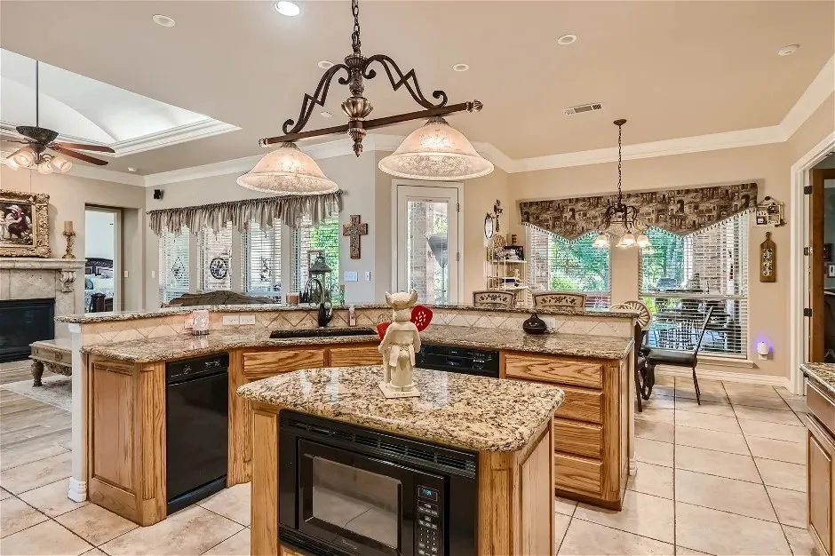 Kitchen featuring granite countertops, wood cabinetry, tile flooring, a built-in microwave, and a breakfast bar