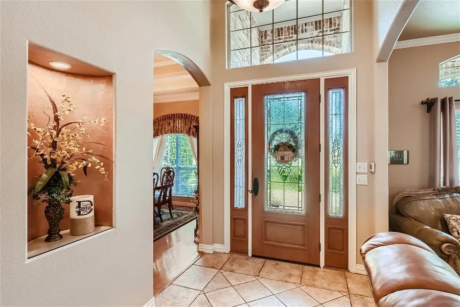 Two-story foyer featuring an arched transom window and leaded glass sidelights and door