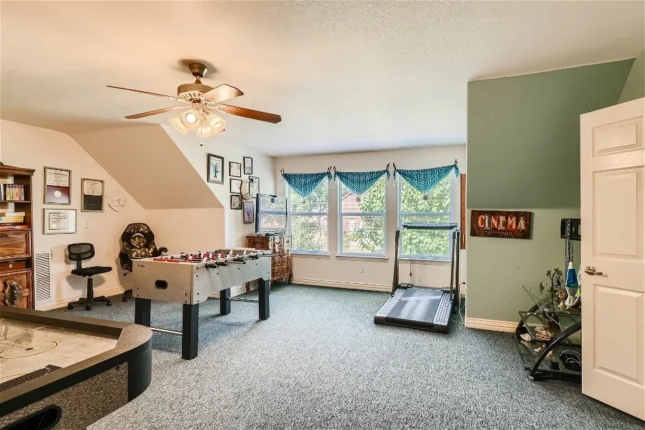 Carpeted bonus room with angled ceilings, a ceiling fan, and multiple windows
