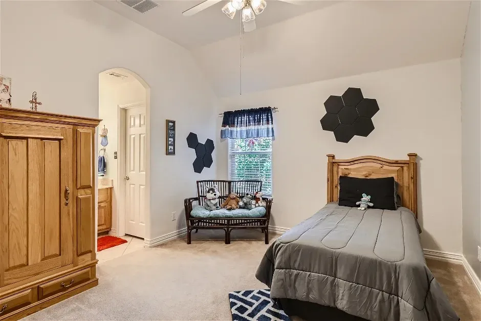 Vaulted ceiling with a ceiling fan, carpeted flooring, and a window with blinds