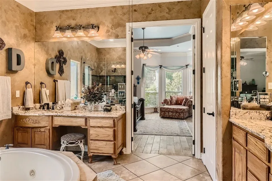 Dual vanities with integrated storage, full-height mirror, and a recessed bathtub
