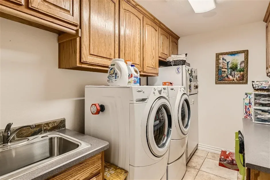 Upper cabinetry, countertop, stainless steel sink, tile backsplash, and tile flooring