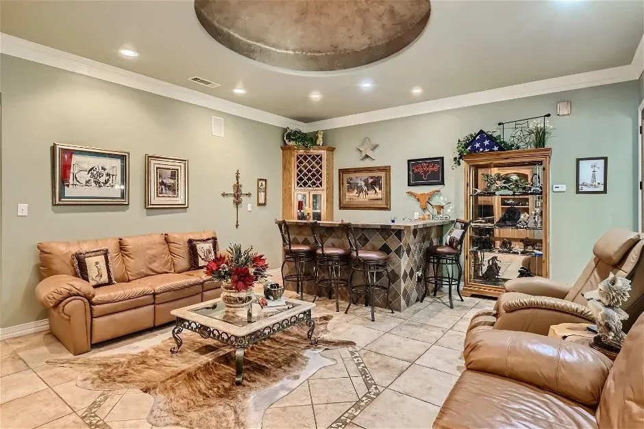 Recessed lighting, crown molding, built-in wet bar with tiled facade, tray ceiling, and tile flooring
