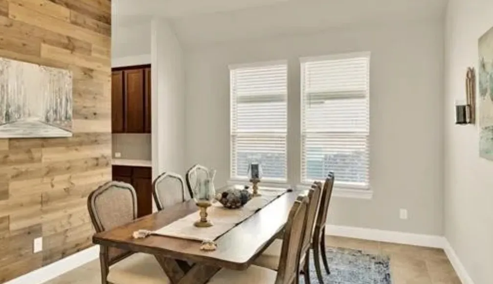 Wood-finish accent wall with two large windows featuring blinds, ceramic tile flooring, and integrated built-in cabinetry
