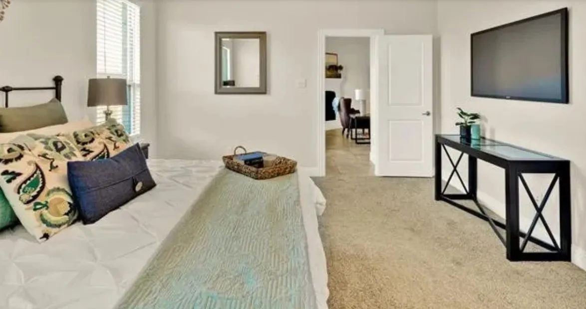 Carpeted flooring, white interior doors, and a wall-mounted flat-screen television