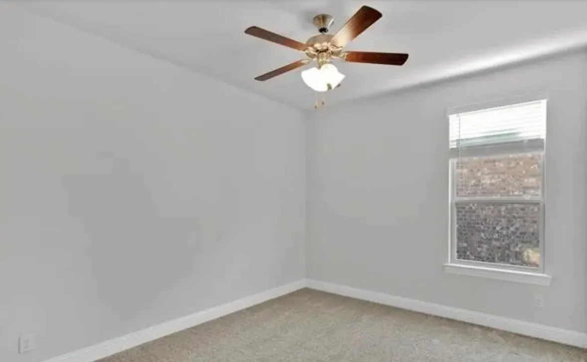 Textured carpeting, neutral wall finishes, window with blinds, and a built-in ceiling fan with integrated lighting