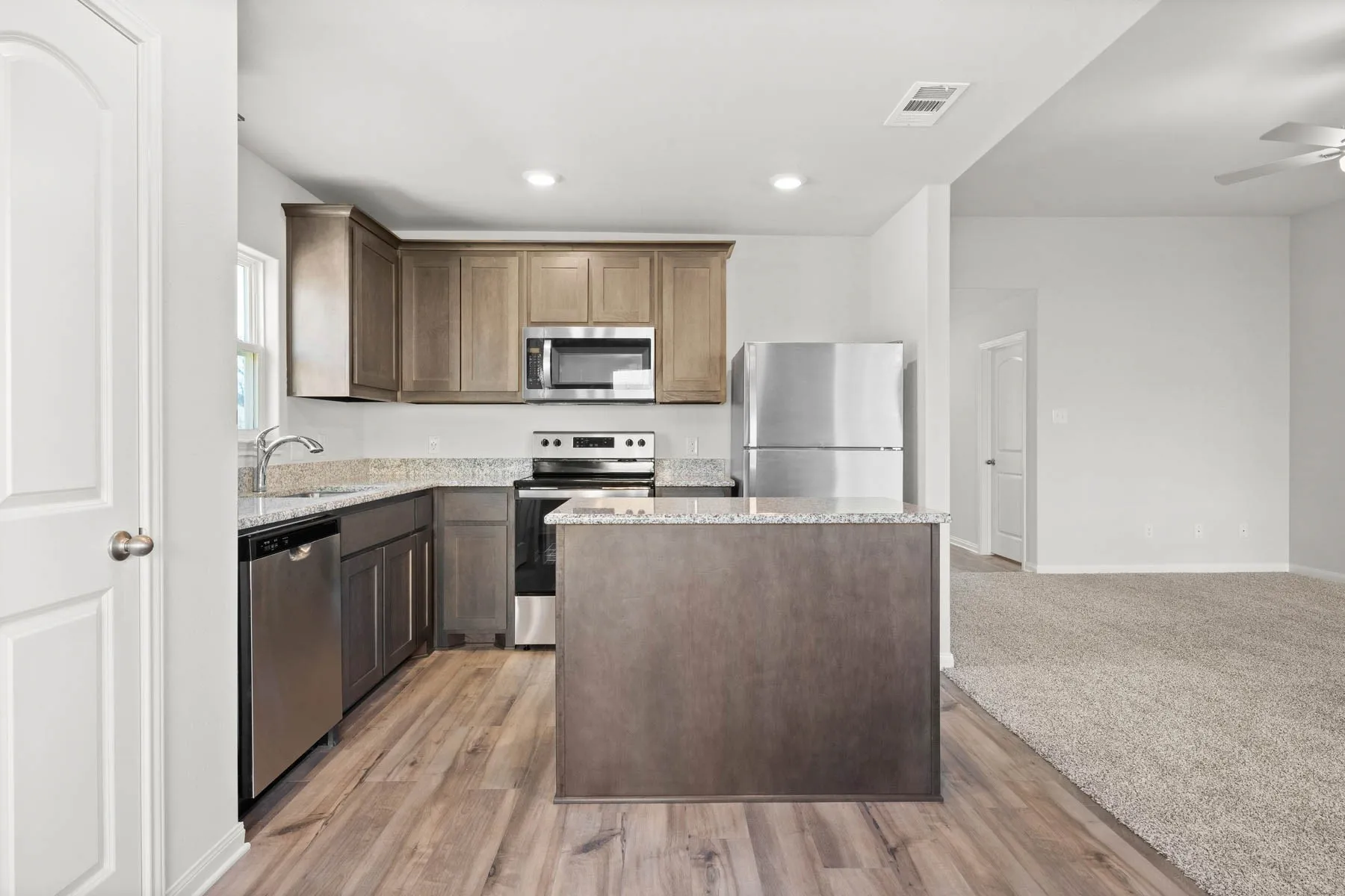 Kitchen with a center island, sink, light hardwood / wood-style flooring, ceiling fan, and appliances with stainless steel finishes