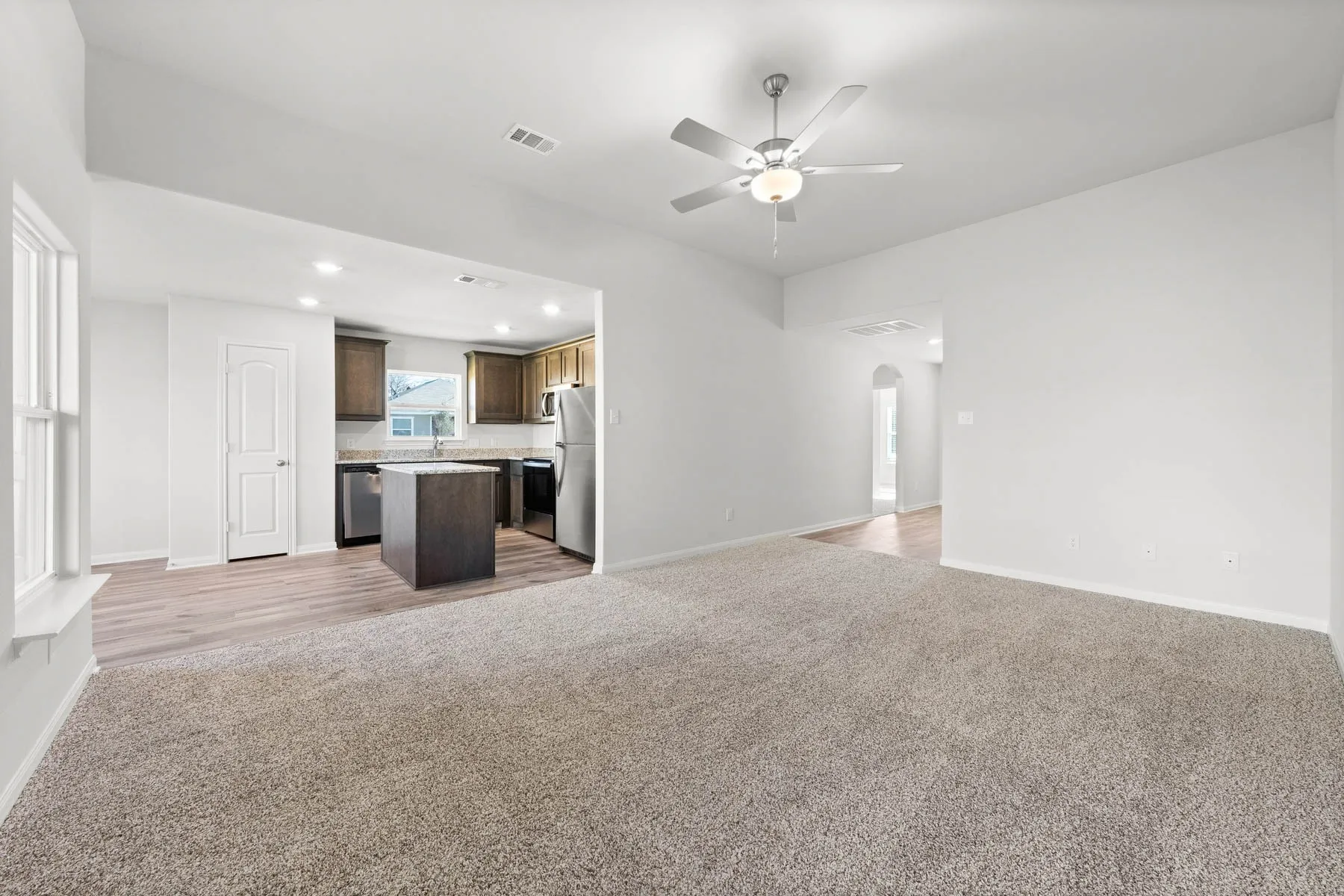 Unfurnished living room featuring carpet flooring, ceiling fan, and sink