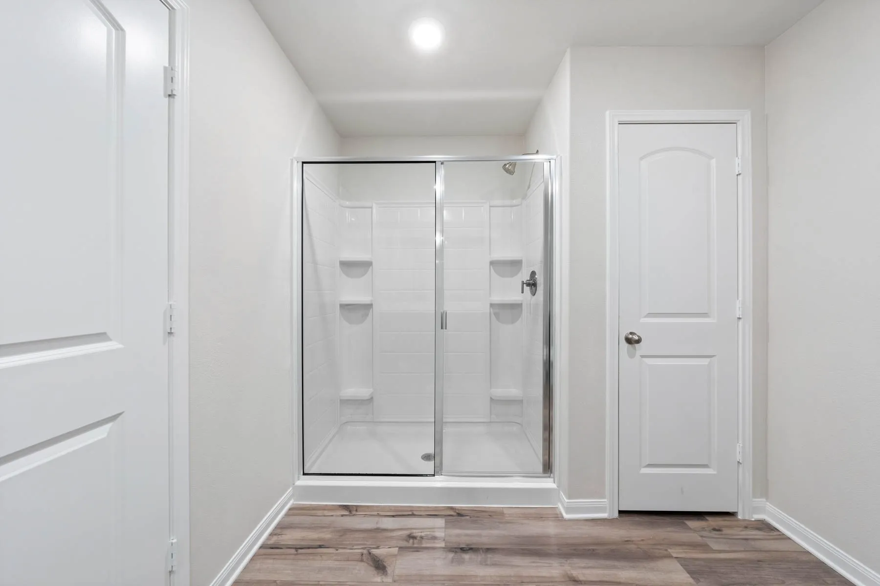 Bathroom featuring wood-type flooring and a shower with shower door