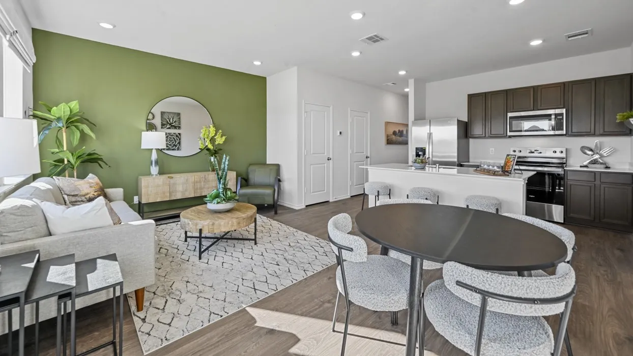 Open-concept living area with wood-finish flooring, recessed lighting, and a kitchen featuring dark wood cabinetry, a white island, and stainless steel appliances