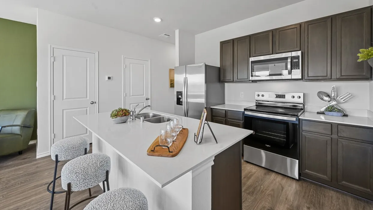 Kitchen featuring a central island with countertop seating, stainless steel appliances, dark wood-finish cabinetry, white countertops, and wood-finish flooring