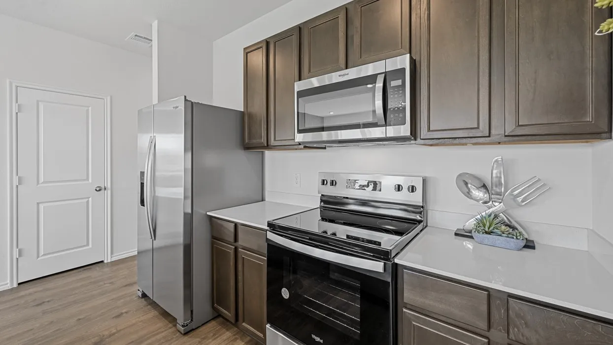 Stainless steel appliances, wood-finish flooring, white countertops, dark wood-finish cabinetry, and an electric range