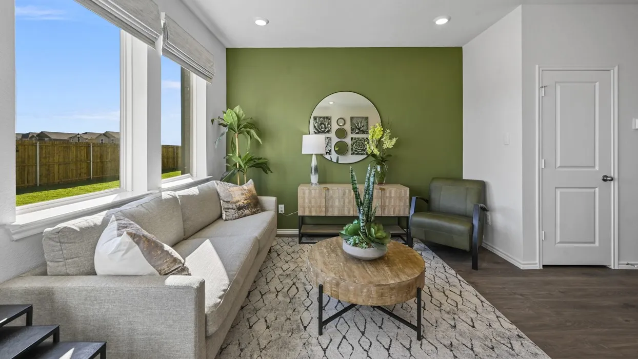 Bright living area featuring large windows with blinds, a prominent accent wall, recessed lighting, and wood-finish flooring