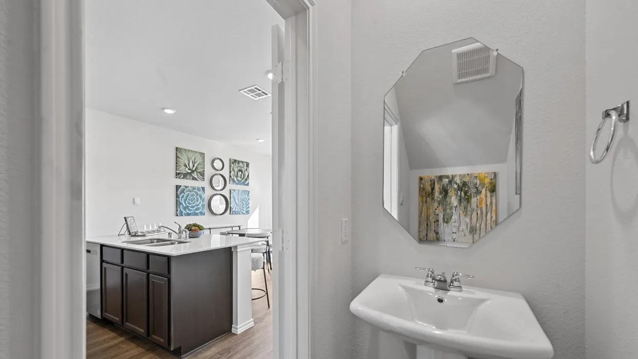 Pedestal sink with chrome fixtures, octagonal mirror, and a towel ring