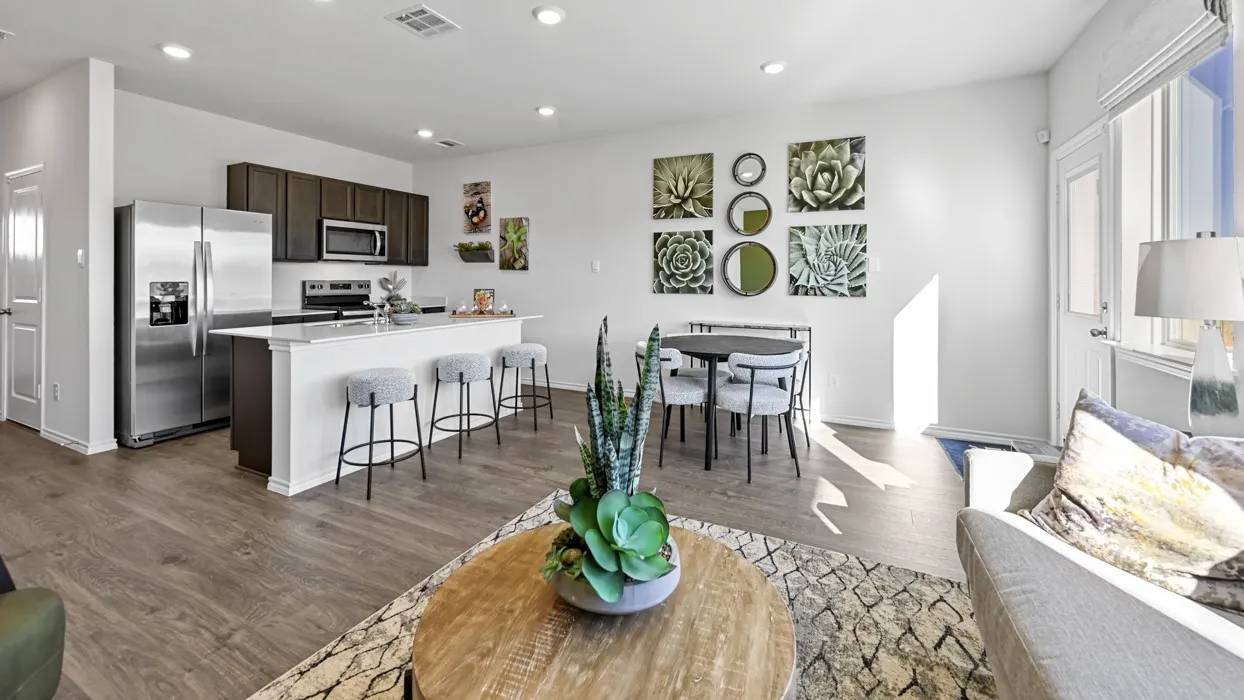 Open-concept living space with wood-finish flooring, recessed lighting, and a kitchen featuring stainless steel appliances and a breakfast bar