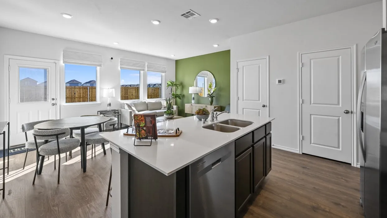 Open concept living area featuring wood-finish flooring, a kitchen island with dual sinks, recessed lighting, and multiple windows