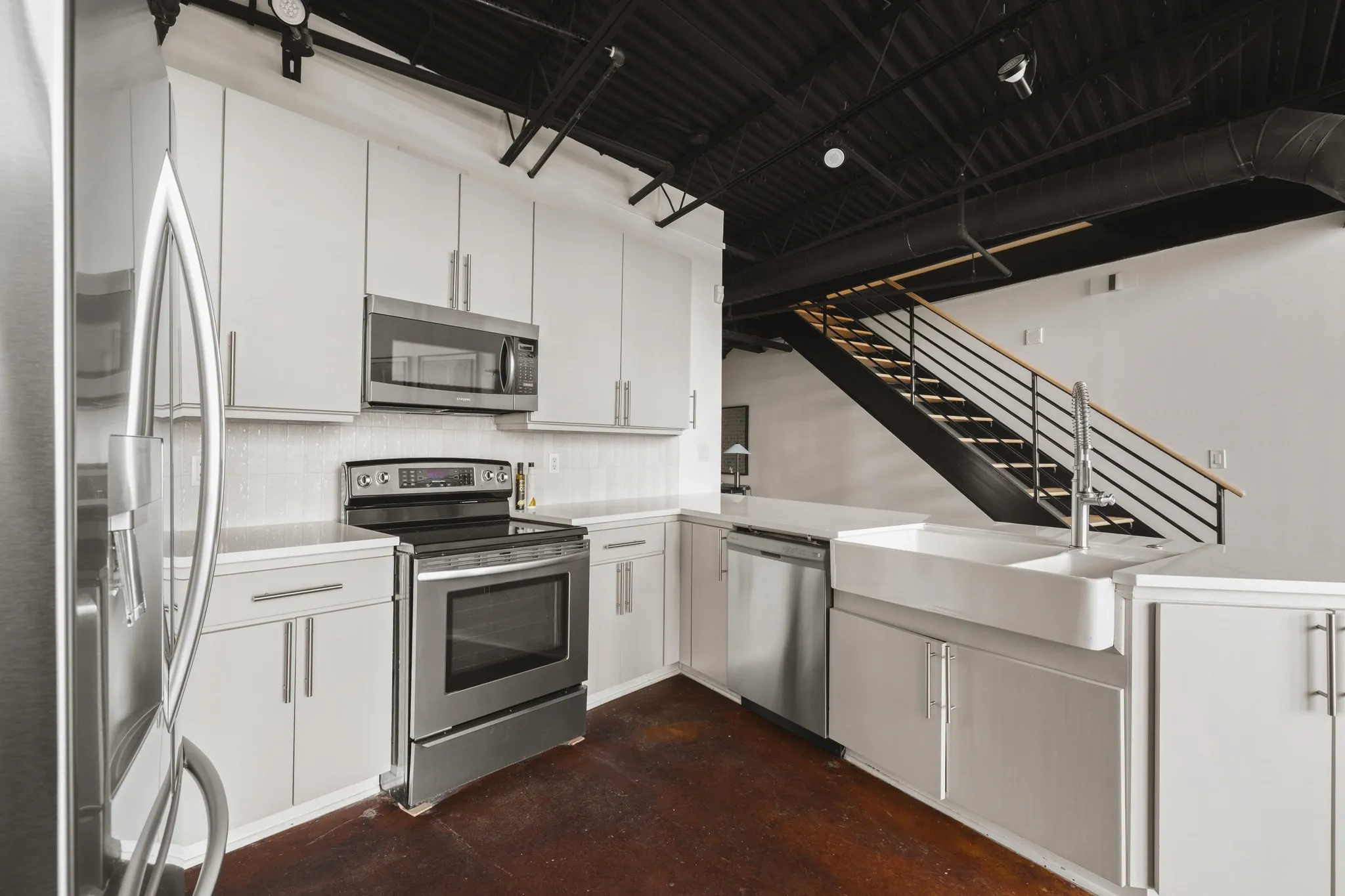 Kitchen featuring stainless steel appliances, white cabinetry, a farmhouse sink, and a white countertop