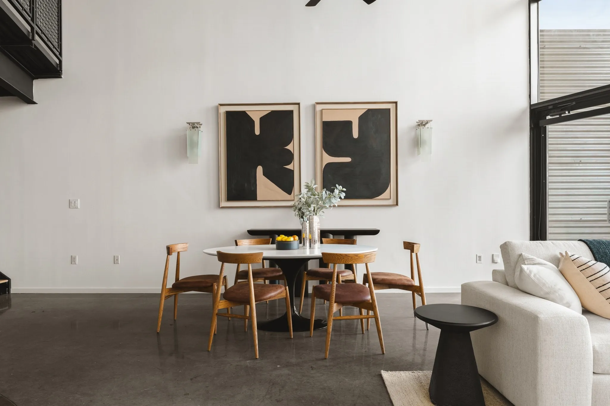 Polished concrete flooring, high ceilings, custom wall sconces, and a black steel open staircase
