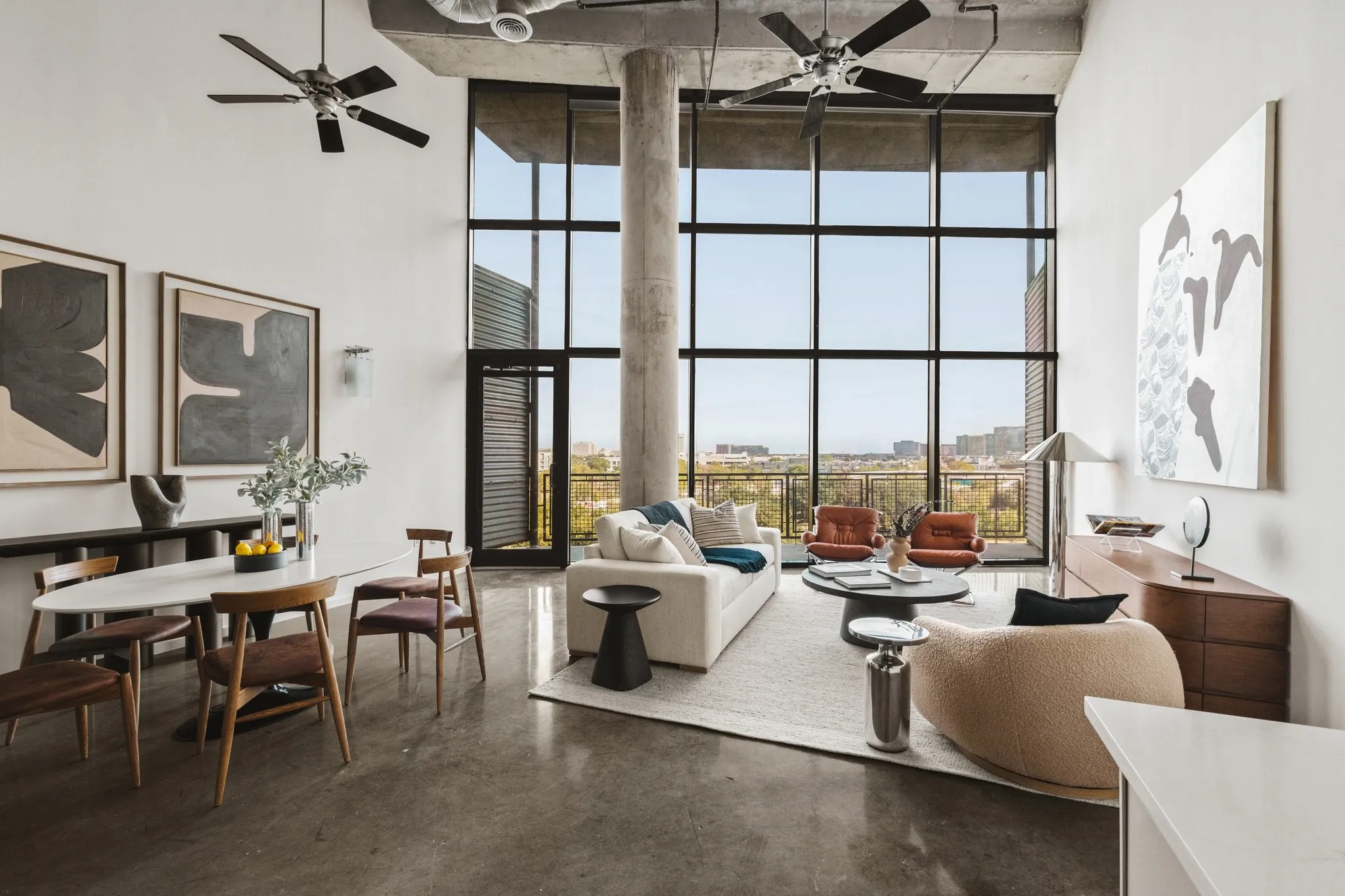 Expansive living area with polished concrete flooring, a full wall of industrial-style windows, exposed concrete ceiling, exposed ductwork, and multiple ceiling fans