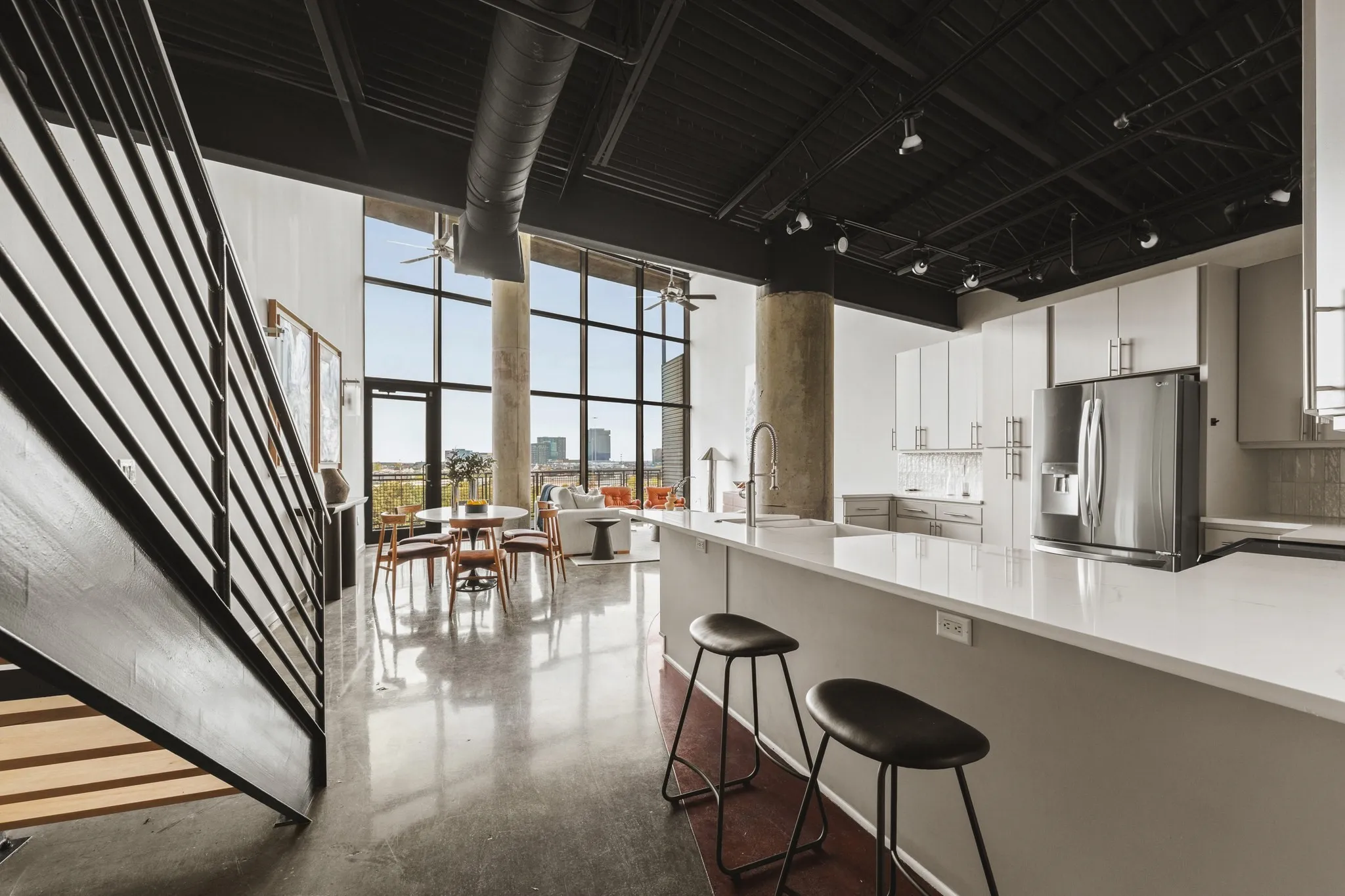 Industrial-style open concept living with exposed ductwork, a concrete structural column, and a black-painted ceiling