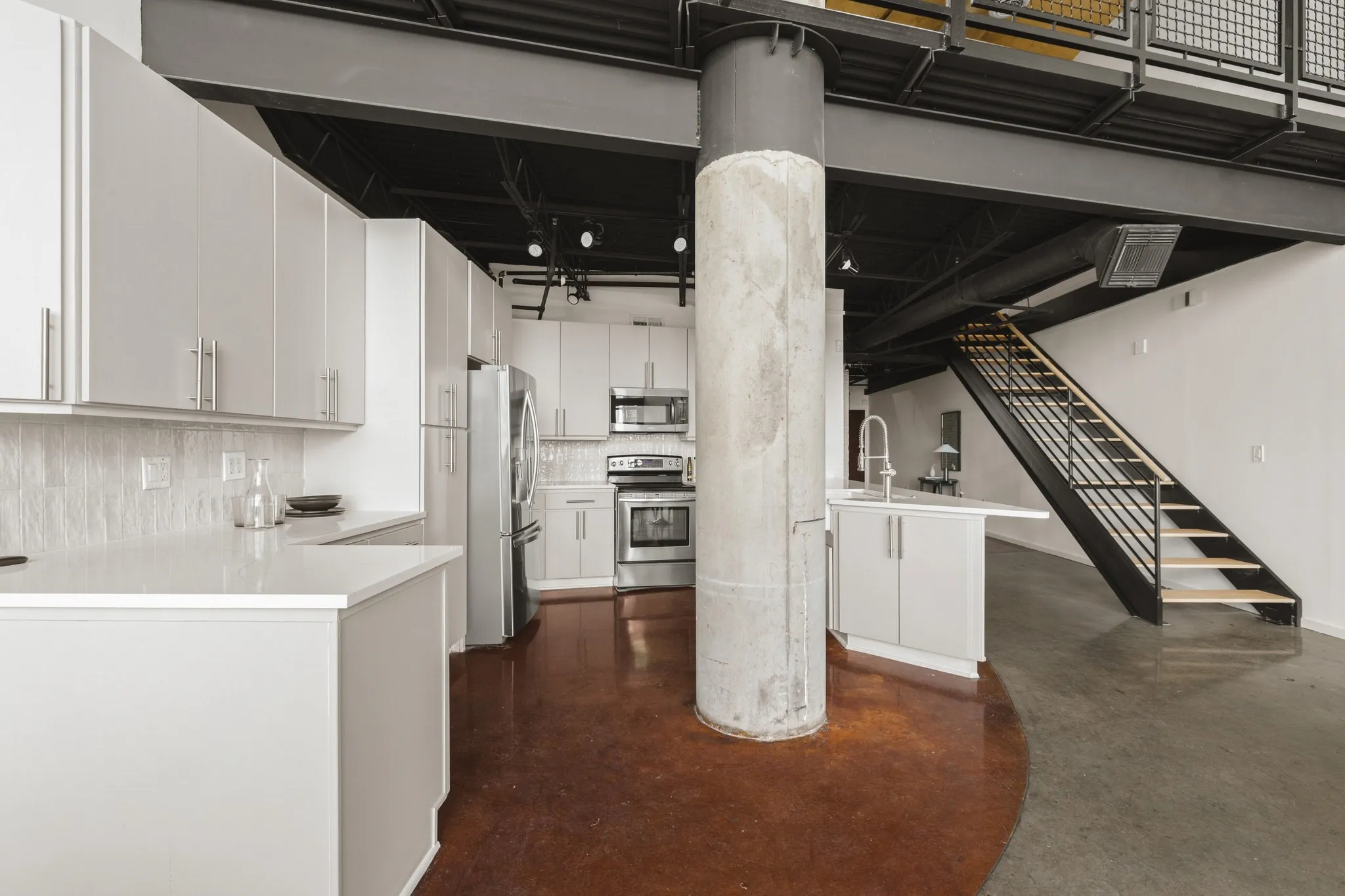 Open-concept kitchen with light cabinetry, stainless steel appliances, and solid surface countertops