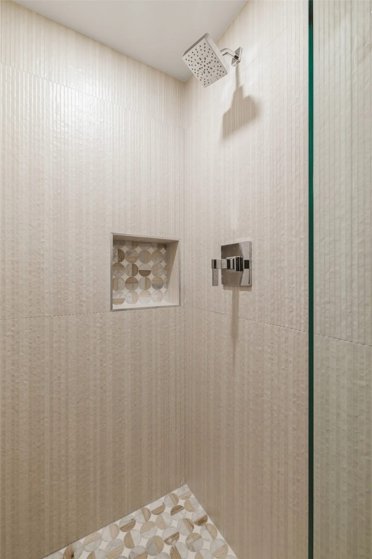 Shower featuring textured wall tile, mosaic tile shower floor, mosaic tile shower niche, and a rain shower head