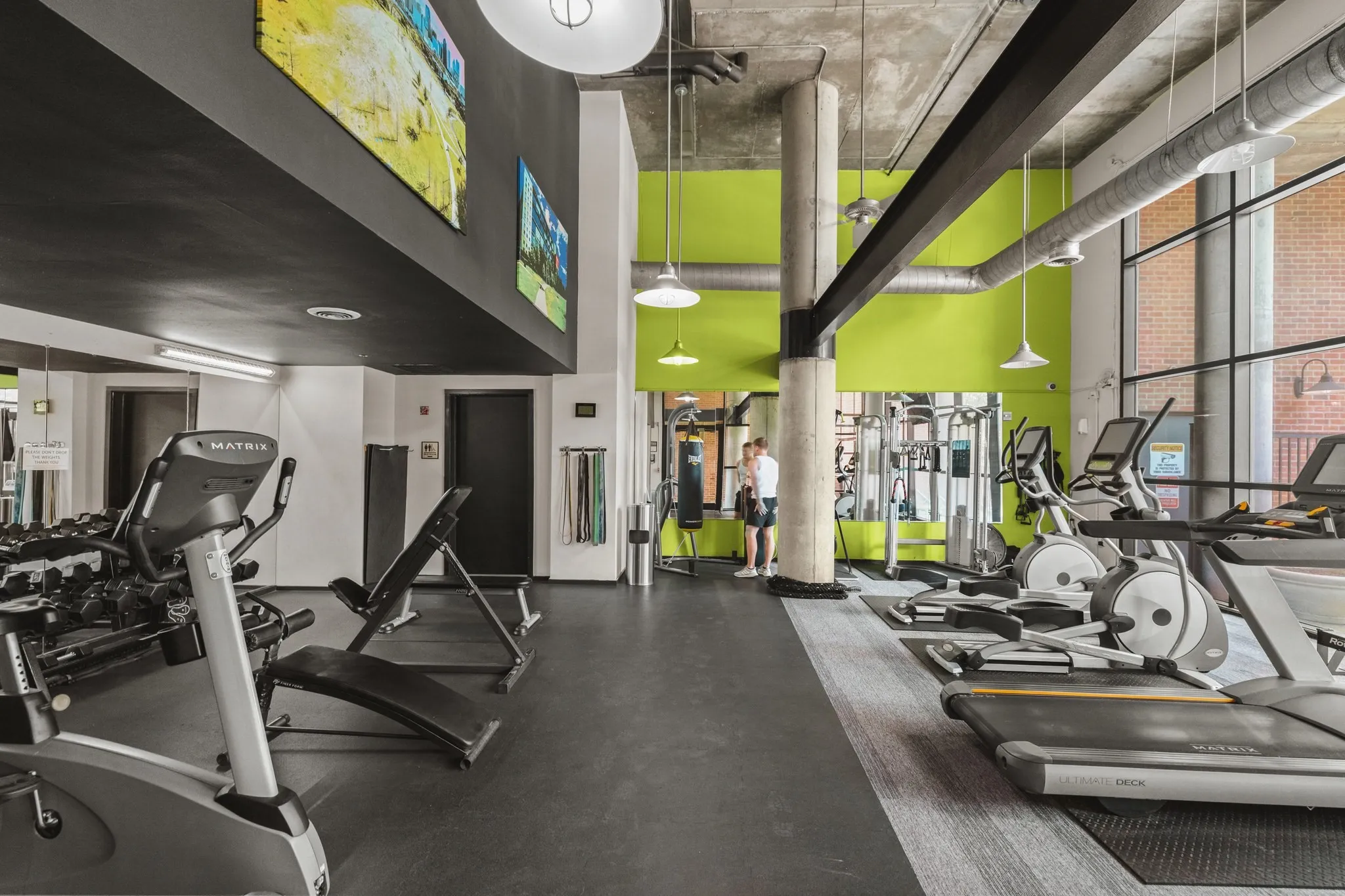 Fitness center with exposed ceiling, large windows, recessed and pendant lighting, and durable flooring
