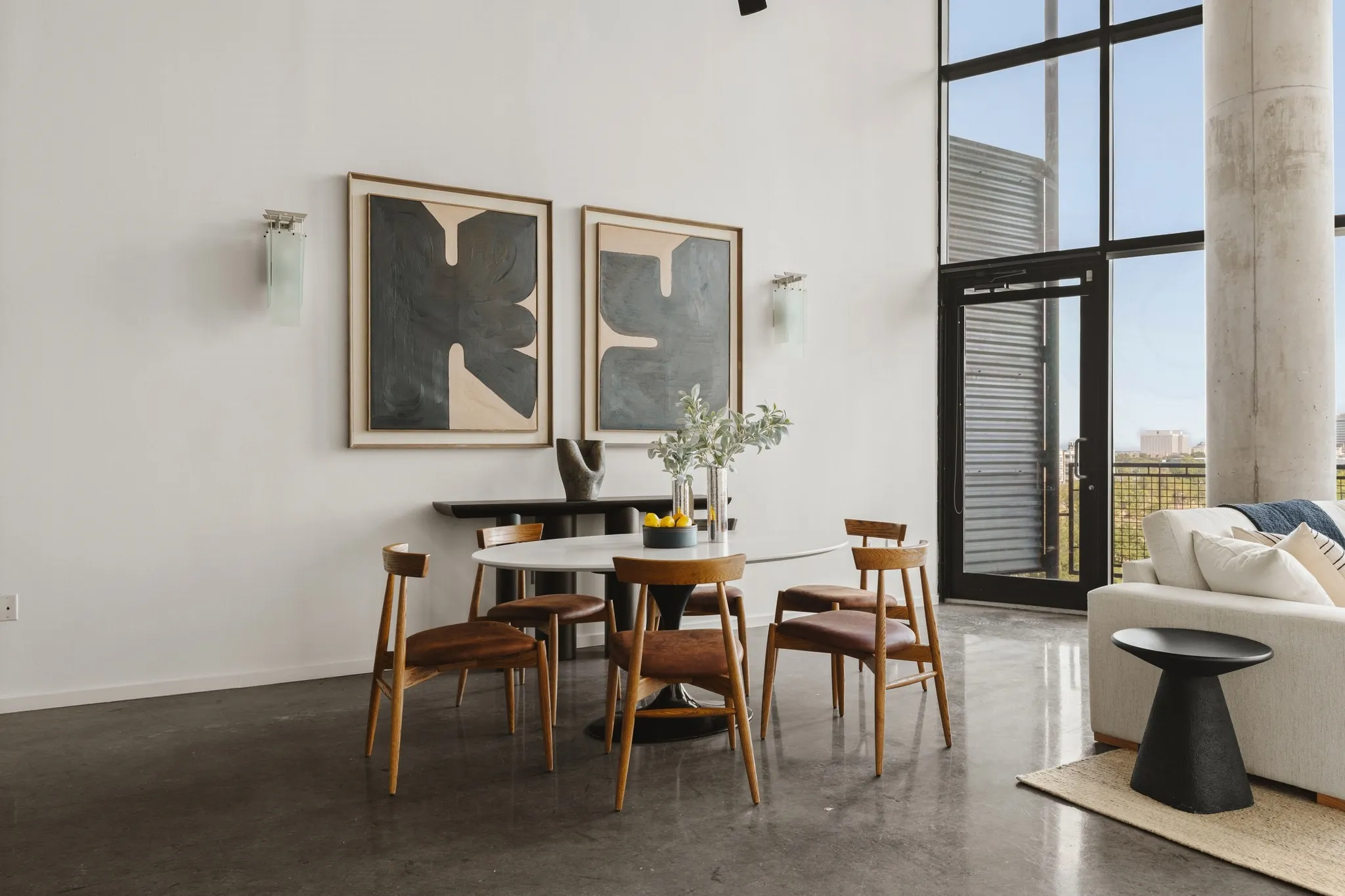 Polished concrete flooring, floor-to-ceiling windows, high ceilings, a balcony with metal railing, and a concrete support column