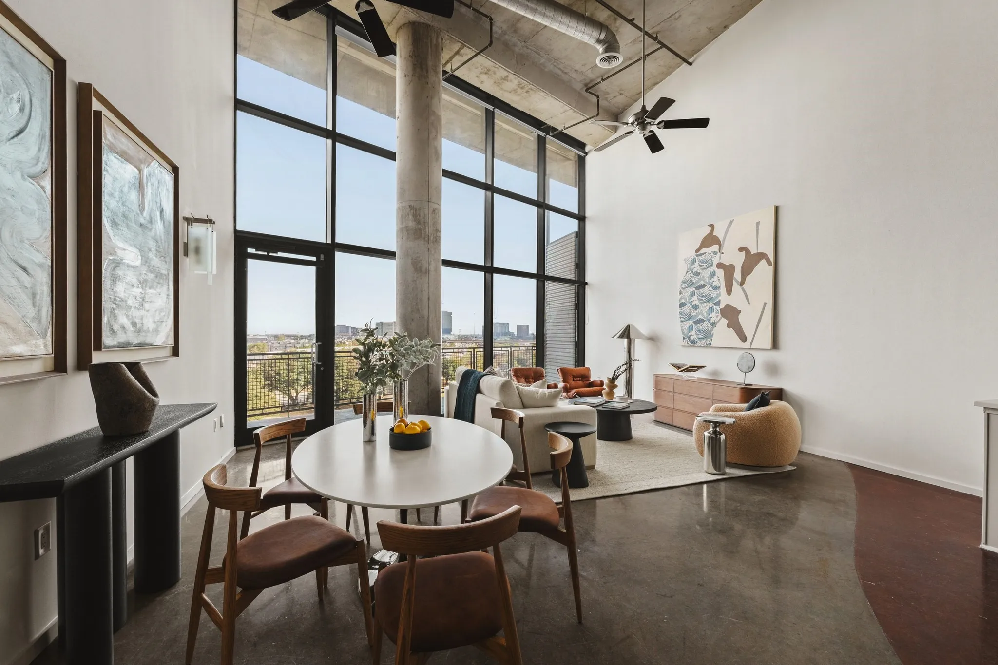Polished concrete flooring, exposed concrete ceiling, industrial-style ceiling fan, full-height window wall with dark framing, and a concrete structural column