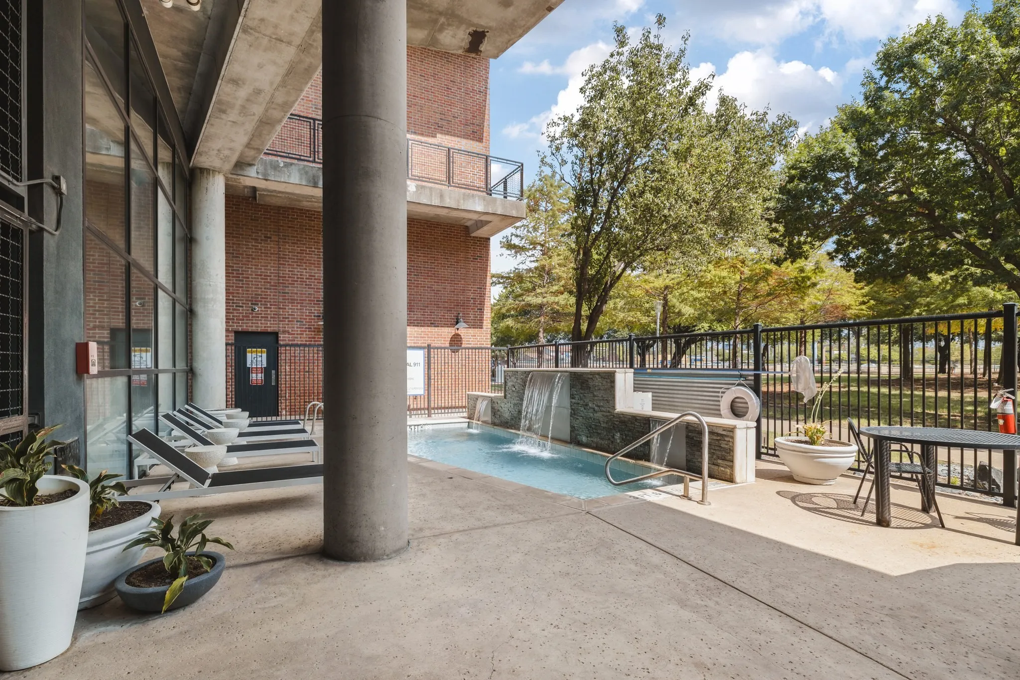 Outdoor aquatic feature with a waterfall, tile surround, and adjacent concrete patio