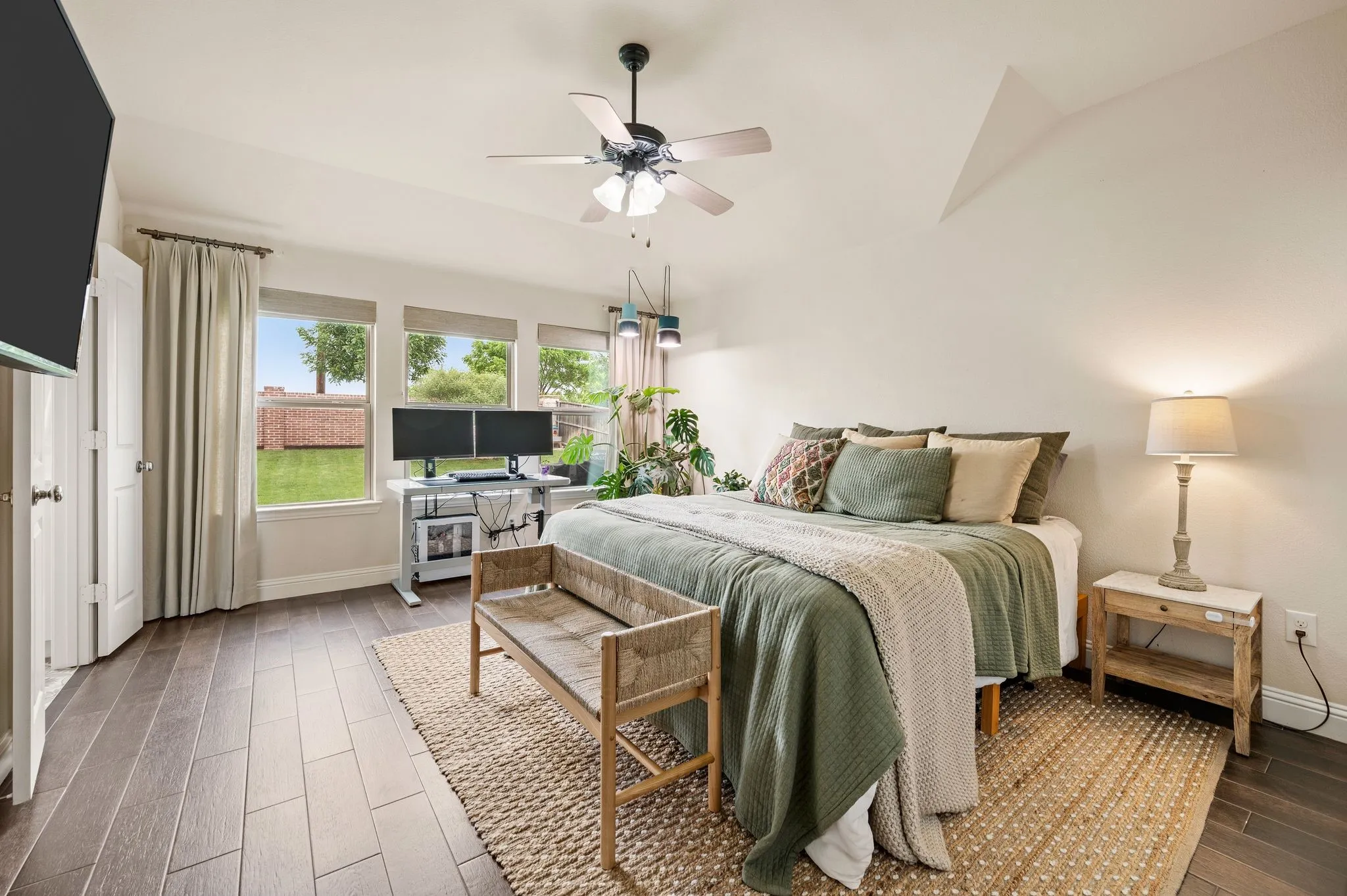 Beautiful flooring, three large windows that let in wonderful natural lighting, ceiling fan with integrated lighting, and a vaulted ceiling accent.  Beautiful custom curtains and roman shades will stay with the home.