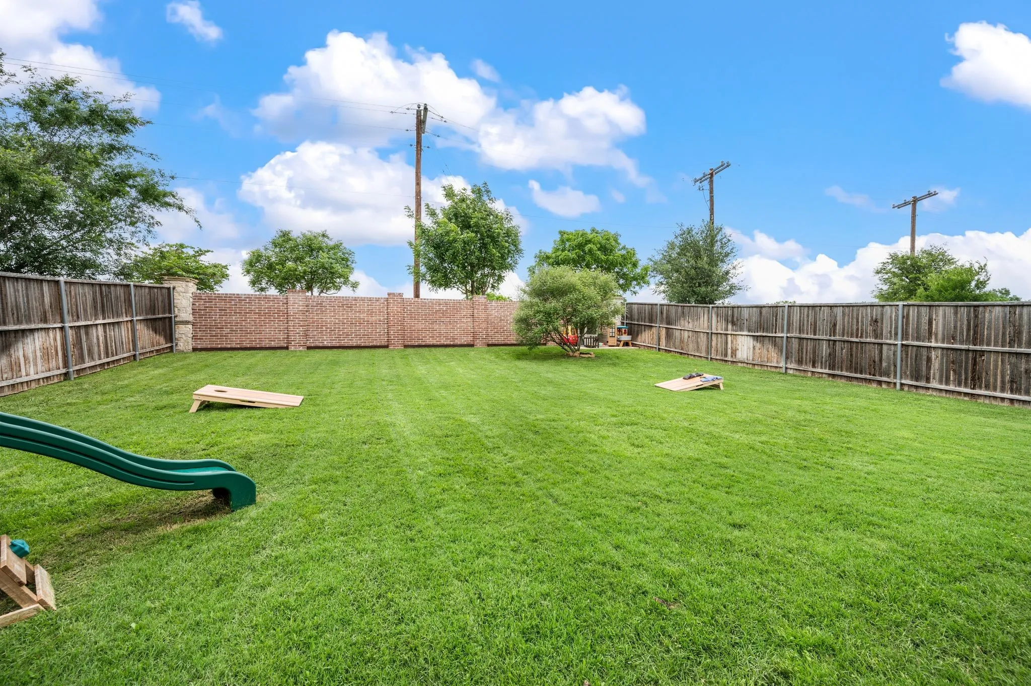 Expansive backyard  that you can put a pool in or a putting green or both...ha...featuring a manicured lawn, brick perimeter wall, and wood fencing