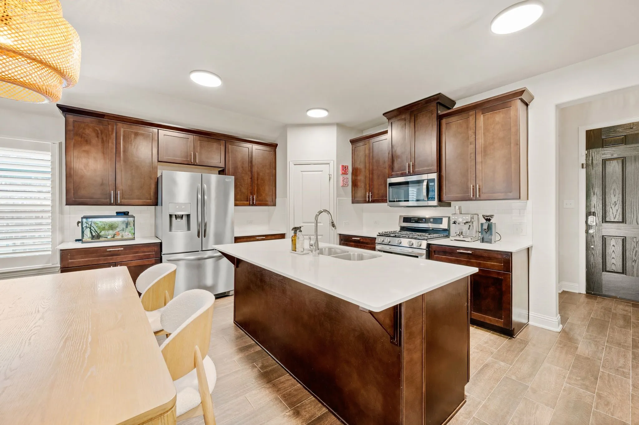 Kitchen featuring beautiful flooring, a ton of cabinetry, quartz countertops, and a large island and stainless steel appliances