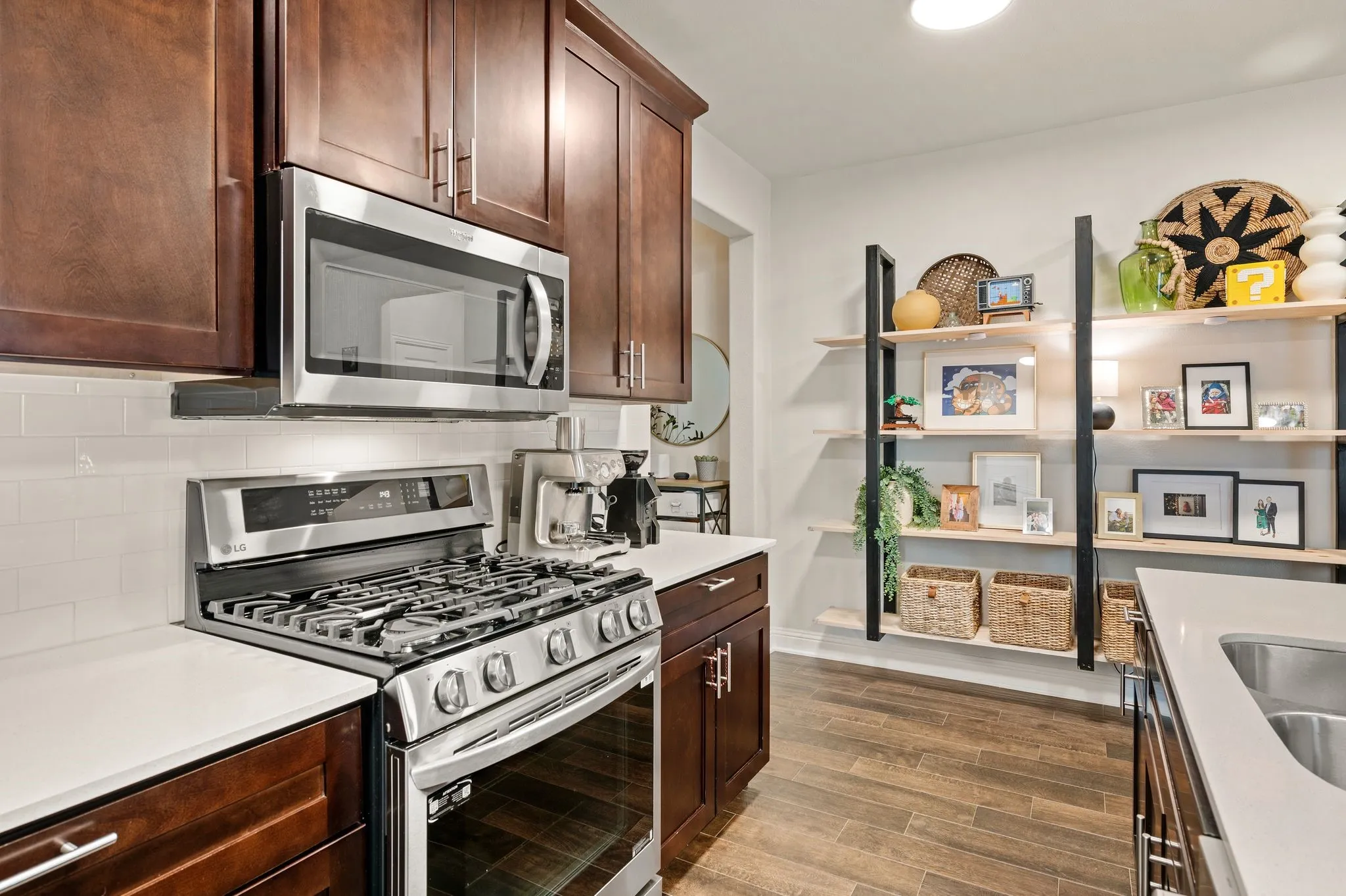 Kitchen featuring rich wood-finish cabinetry, stainless steel appliances, white subway tile backsplash, light-toned countertops, and wood-look flooring
