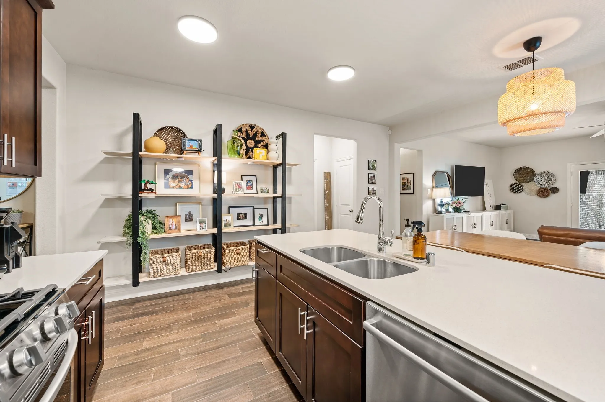 Kitchen featuring beautiful updated flooring, dark wood cabinetry, quartz countertops, stainless steel appliances, and a large eat at island with extra seating
