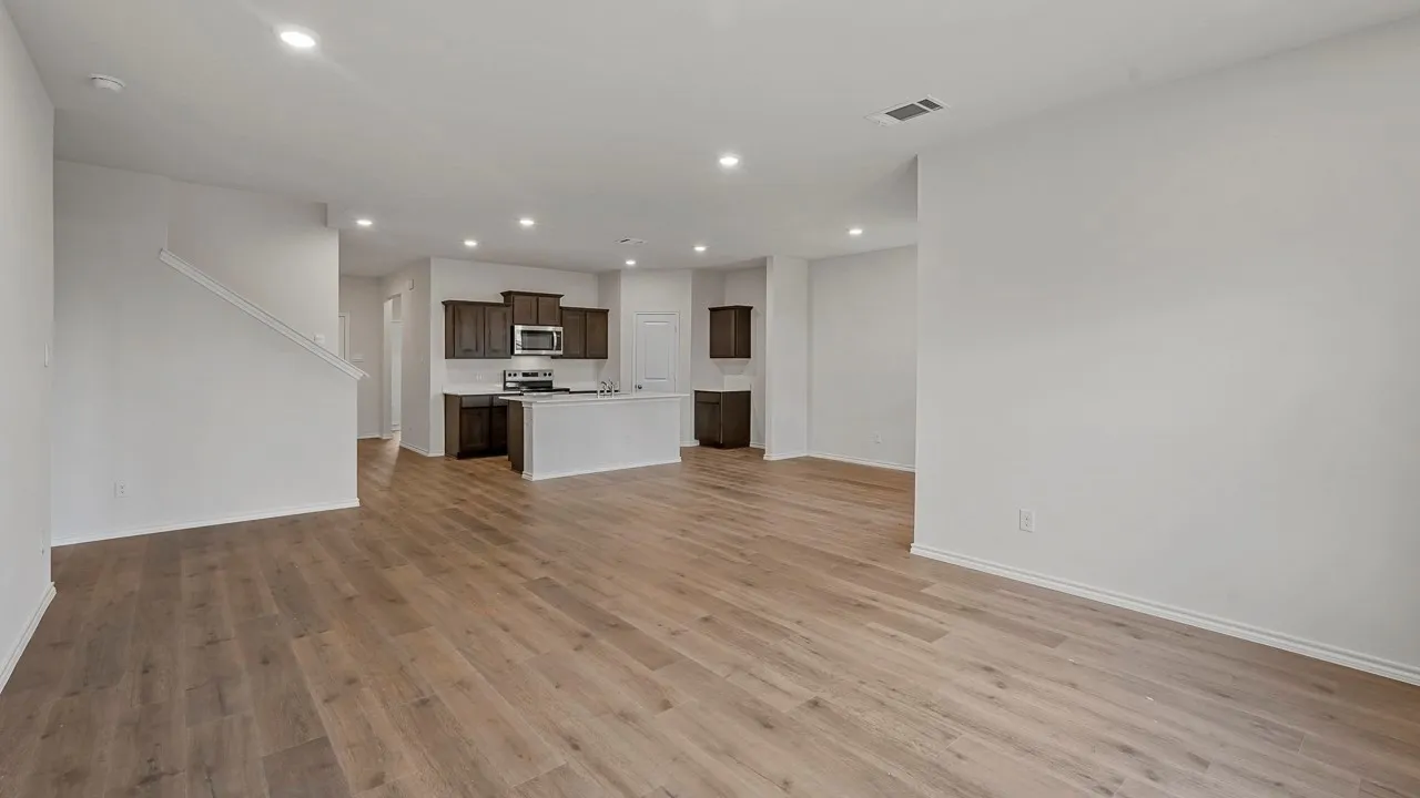 Spacious interior with wood-finish flooring, recessed lighting, and a kitchen featuring dark wood cabinetry, a center island, and stainless steel appliances