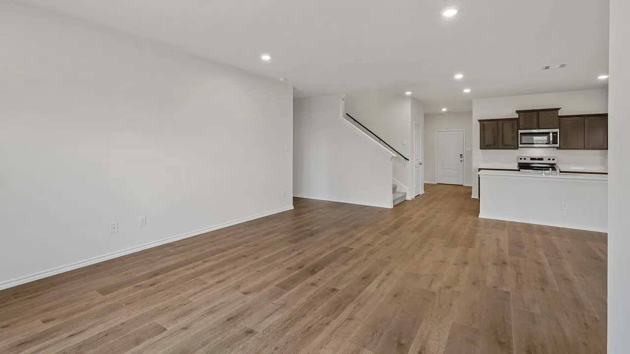 Open-concept living area with wood-finish flooring, recessed lighting, and a modern kitchen